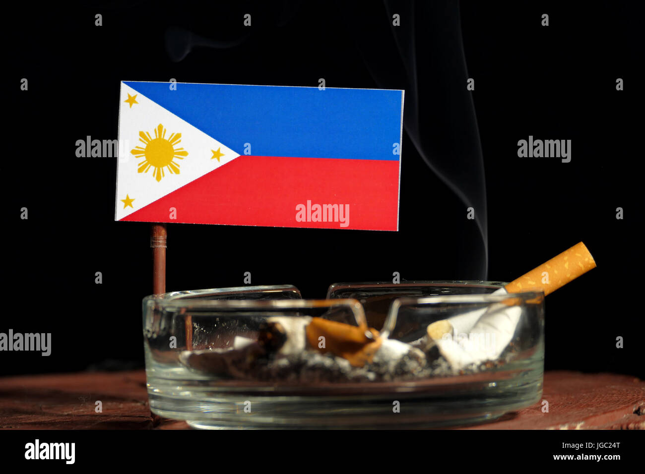 Philippines flag with burning cigarette in ashtray isolated on black