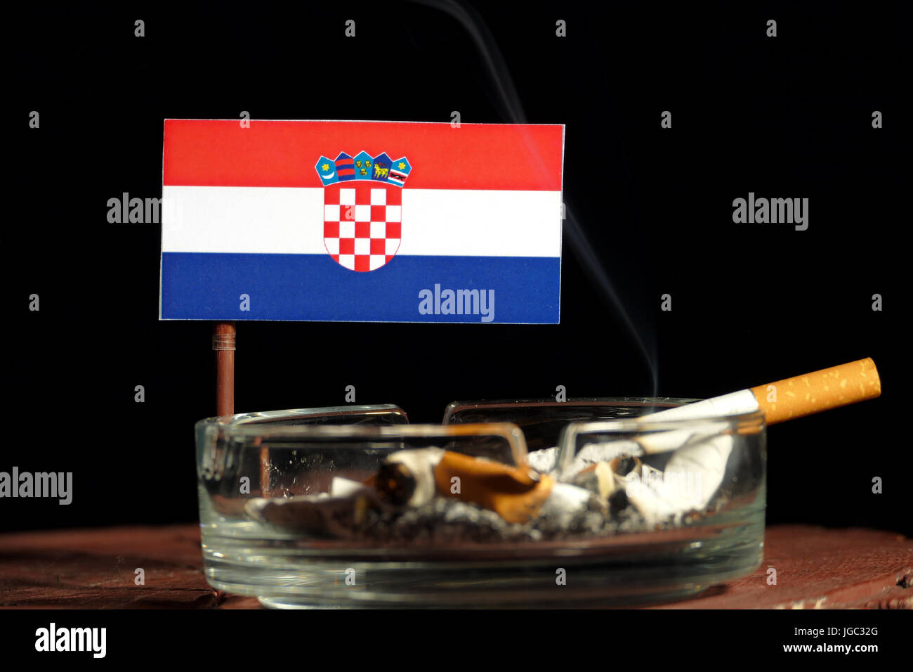 Croatian flag with burning cigarette in ashtray isolated on black  background Stock Photo