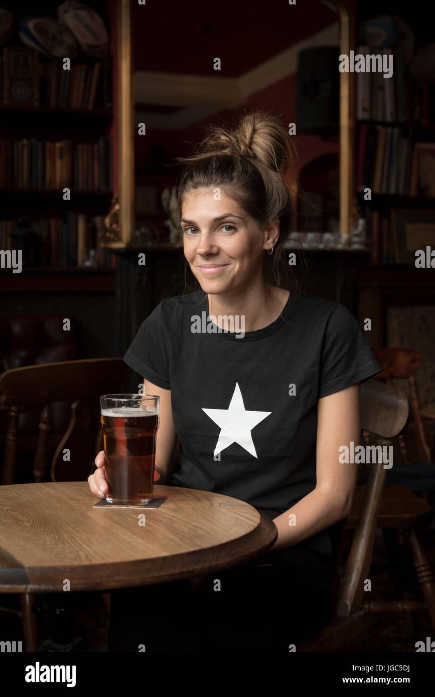 A modern young woman drinking real ale in a London pub Stock Photo