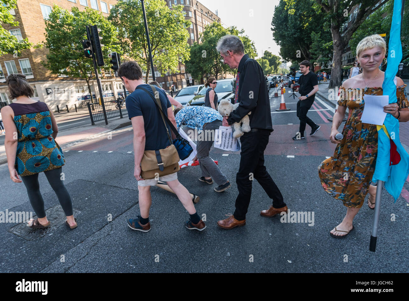 London, UK. 5th July 2017. Rising Up campaigners walk into the road for their brief 'Staying' Alive' road-block disco on the east-bound carriageway of the Marylebone Road near Baker St to raise awareness about the terribly high pollution levels on London streets caused largely by traffic. They walked onto a pedestrian crossing, raised a banner, spoke briefly about the problem and then danced, holding up notices to the blocked motorists apologising  for the protest but pointing out that urgent action was needed and the protest would be short. One Volvo driver got out of his car and argued angri Stock Photo