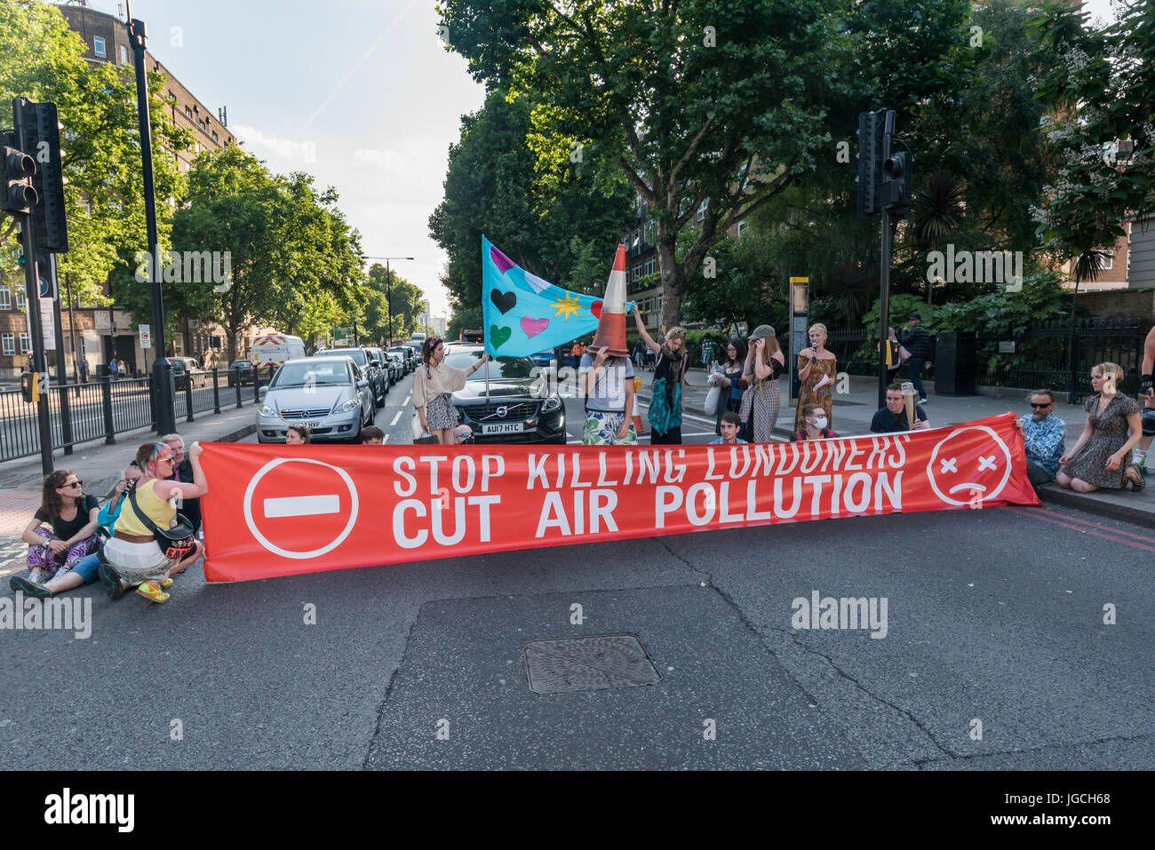 London, UK. 5th July 2017. Rising Up campaigners block the Marylebone Road with a banner reading 'Stop Killing Londoners - Cut Air Pollution' for their brief road-block disco on the east-bound carriageway near Baker St to raise awareness about the terribly high pollution levels on London streets caused largely by traffic. They walked onto a pedestrian crossing, raised a banner, spoke briefly about the problem and then danced, holding up notices to the blocked motorists apologising  for the protest but pointing out that urgent action was needed and the protest would be short. One Volvo driver g Stock Photo