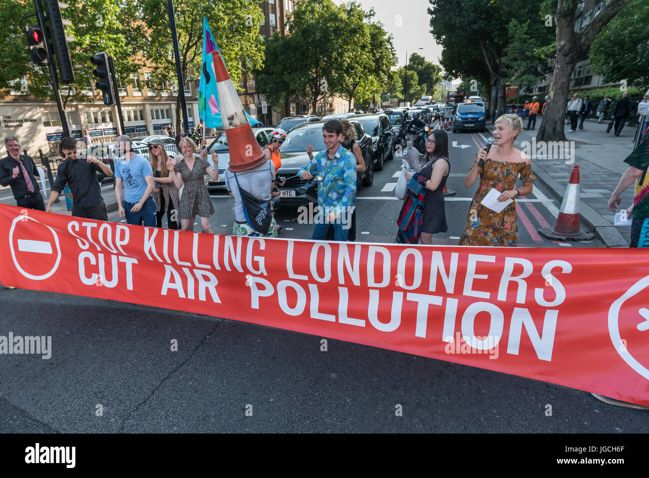 London, UK. 5th July 2017. Rising Up campaigners block the Marylebone Road with a banner reading 'Stop Killing Londoners - Cut Air Pollution' for their brief road-block disco on the east-bound carriageway near Baker St to raise awareness about the terribly high pollution levels on London streets caused largely by traffic. They walked onto a pedestrian crossing, raised a banner, spoke briefly about the problem and then danced, holding up notices to the blocked motorists apologising  for the protest but pointing out that urgent action was needed and the protest would be short. One Volvo driver g Stock Photo