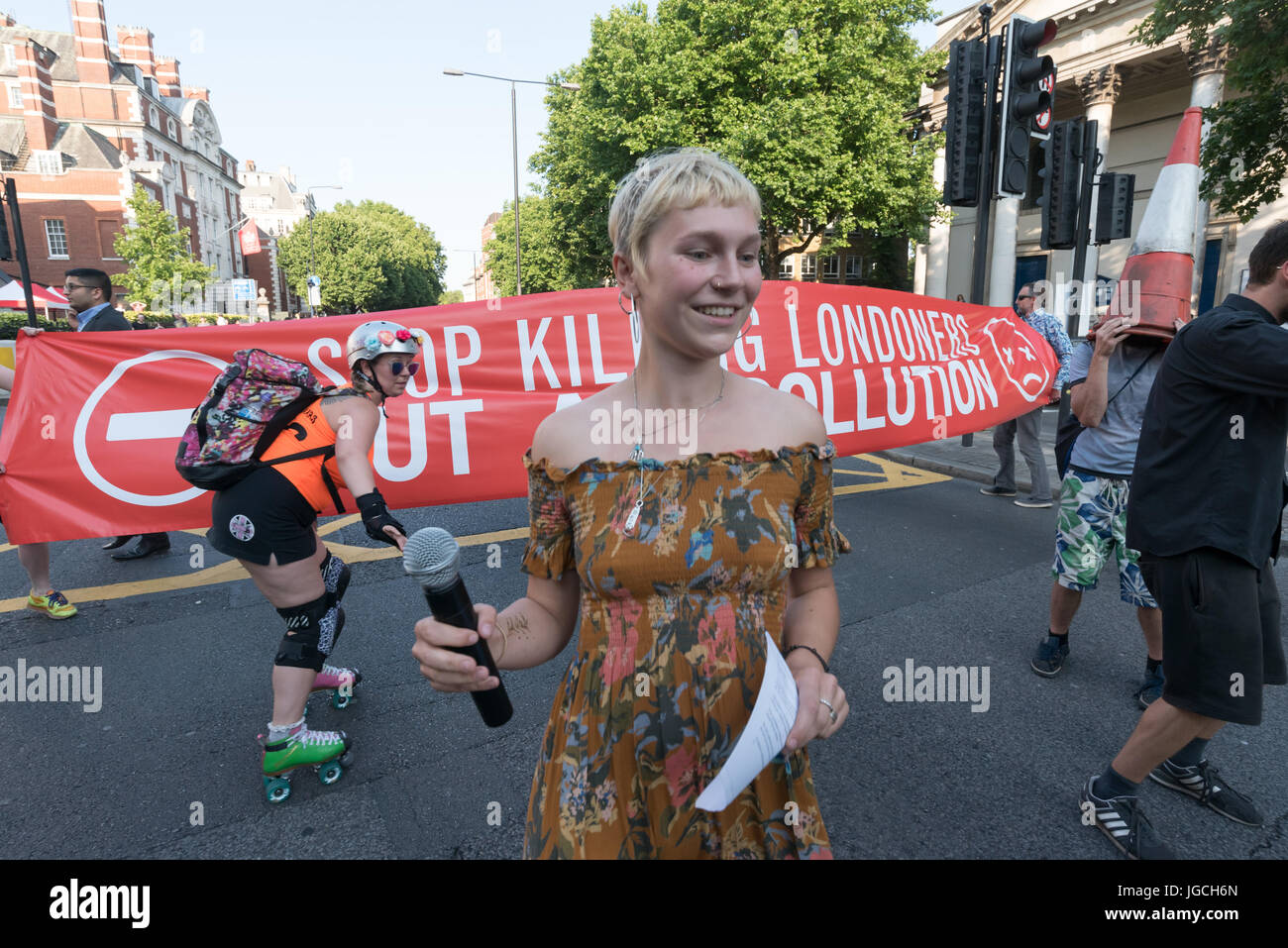 London, UK. 5th July 2017. Rising Up campaigners dance on the Marylebone Road   in their brief 'Stop Killing Londoners - Cut Air Pollution' road-block disco on the east-bound carriageway near Baker St to raise awareness about the terribly high pollution levels on London streets caused largely by traffic. They walked onto a pedestrian crossing, raised a banner, spoke briefly about the problem and then danced, holding up notices to the blocked motorists apologising  for the protest but pointing out that urgent action was needed and the protest would be short. One Volvo driver got out of his car  Stock Photo