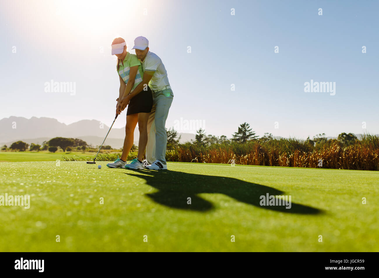 Male golf instructor teaching female golf player, personal trainer giving  lesson on golf course. Male showing woman to play golf Stock Photo - Alamy
