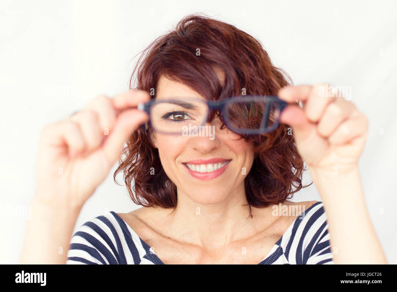 Smiling woman holding a pair of spectacles Stock Photo