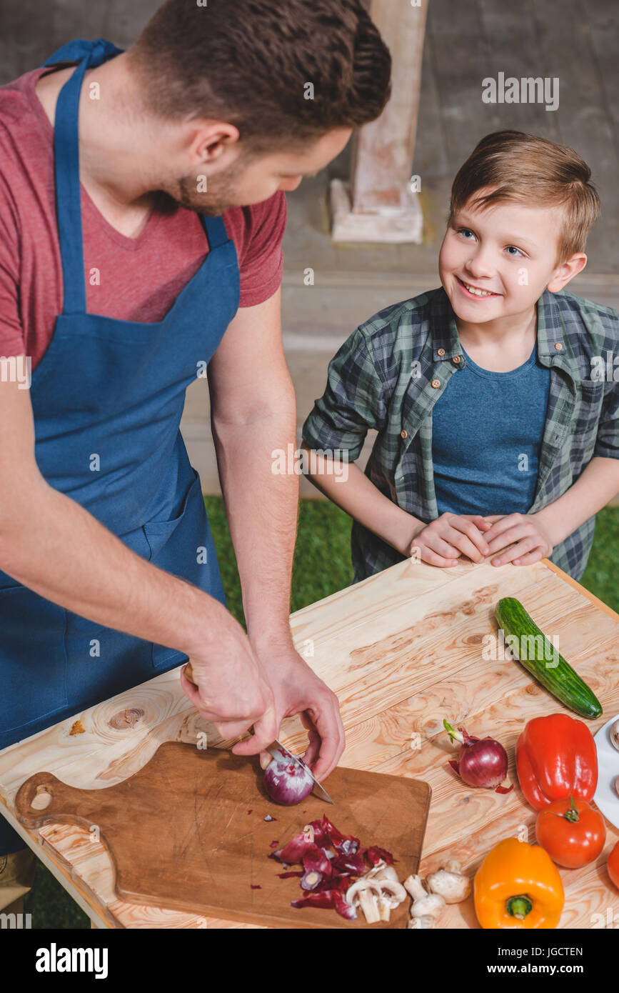 father with little son preparing food on table at backyard, dad and son cooking Stock Photo