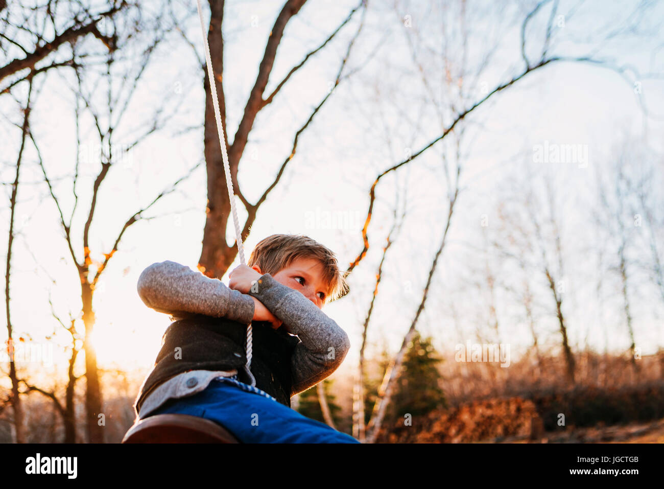 Boy swinging on a rope swing Stock Photo