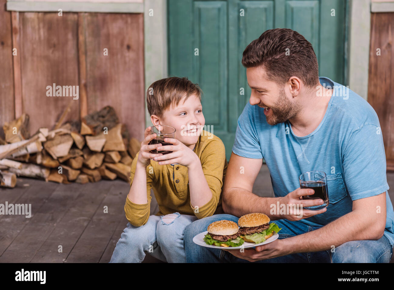 portrait of happy father and son eating homemade burgers Stock Photo