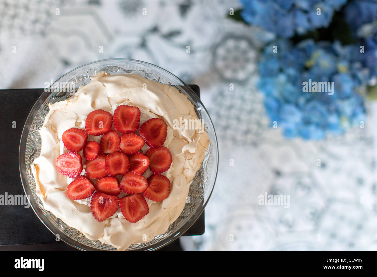 Overhead view of a strawberry pavolva cake with flowers Stock Photo