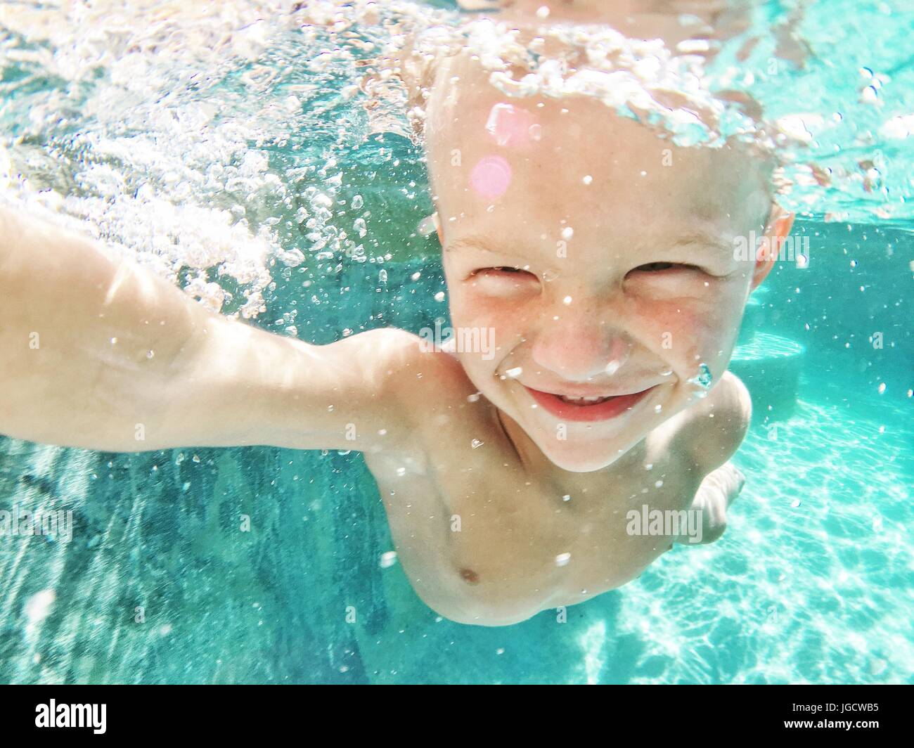 Smiling boy underwater swimming in a swimming pool Stock Photo