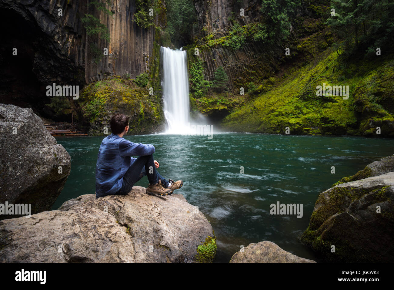 Man sitting on rocks by Toketee Falls, Oregon, United States Stock Photo