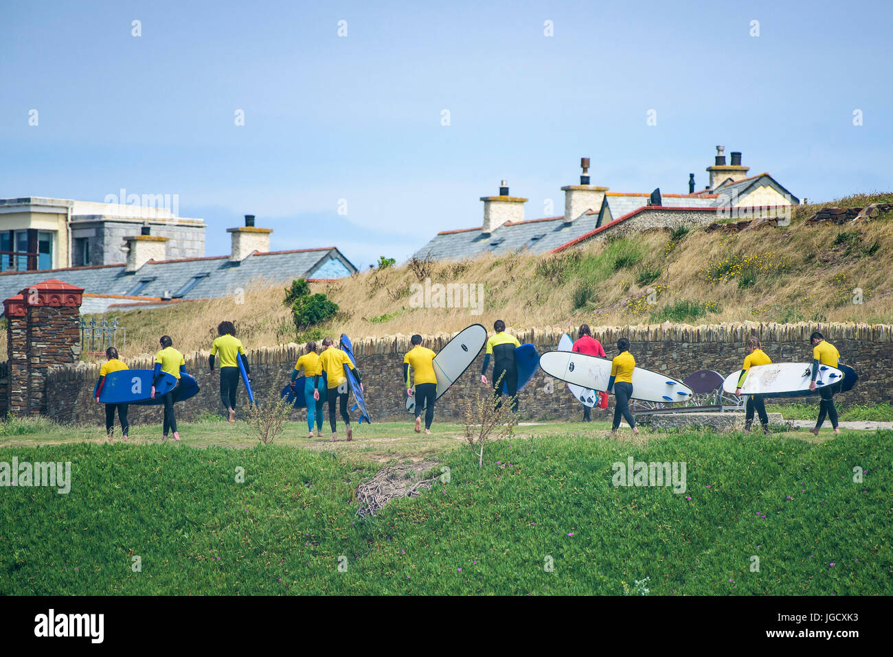 A surf school instructor walking his novices on a footpath on The Headland at Fistral Beach in Newquay, Cornwall; Stock Photo