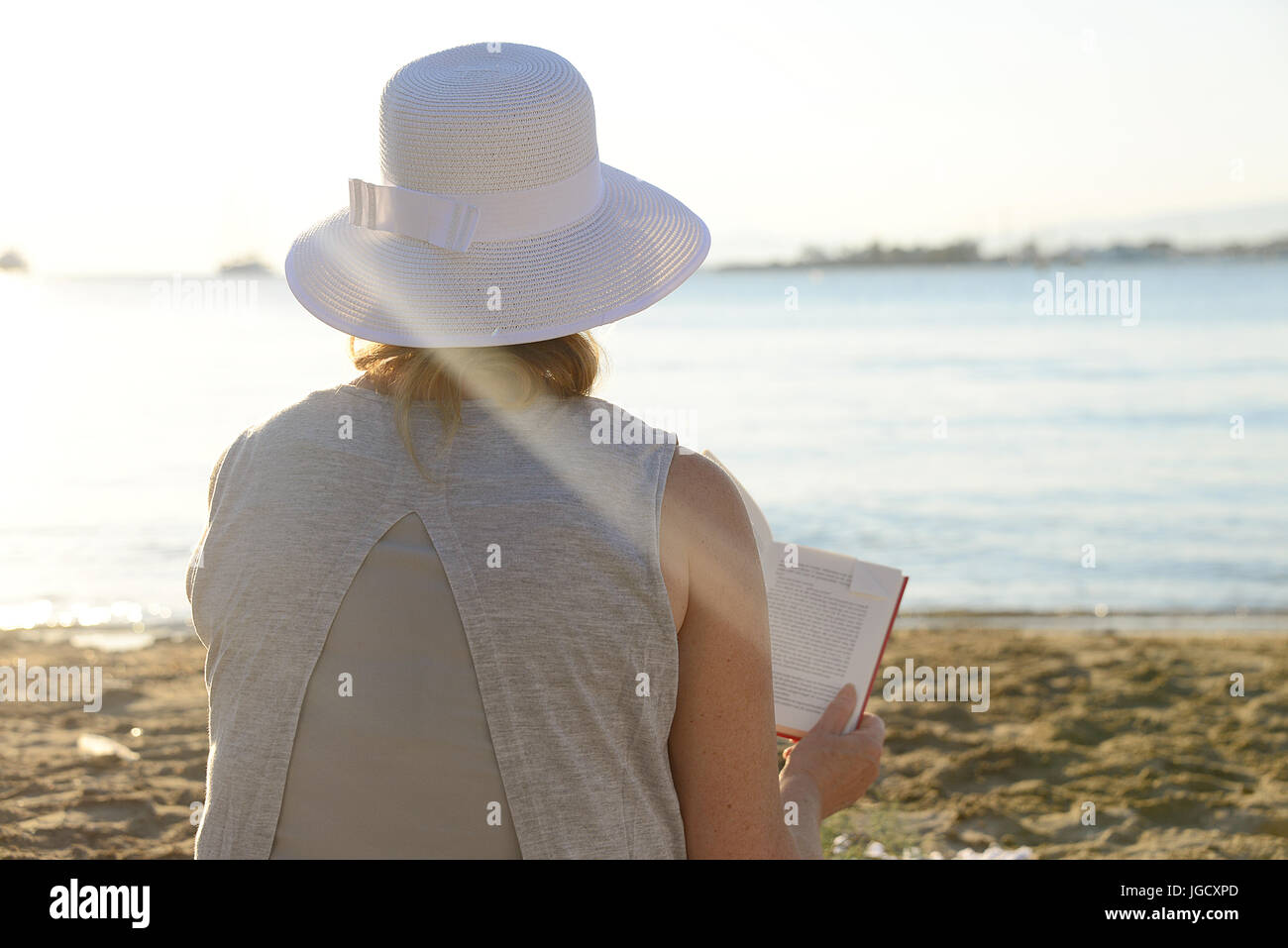 Woman siting at the beach reading a book Stock Photo