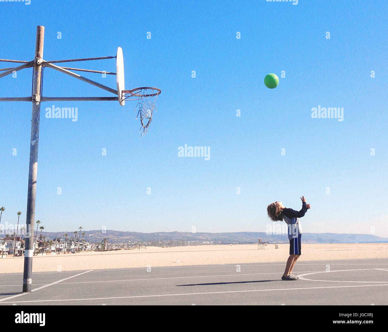 Boy shooting hoops on basketball court, California, United States Stock