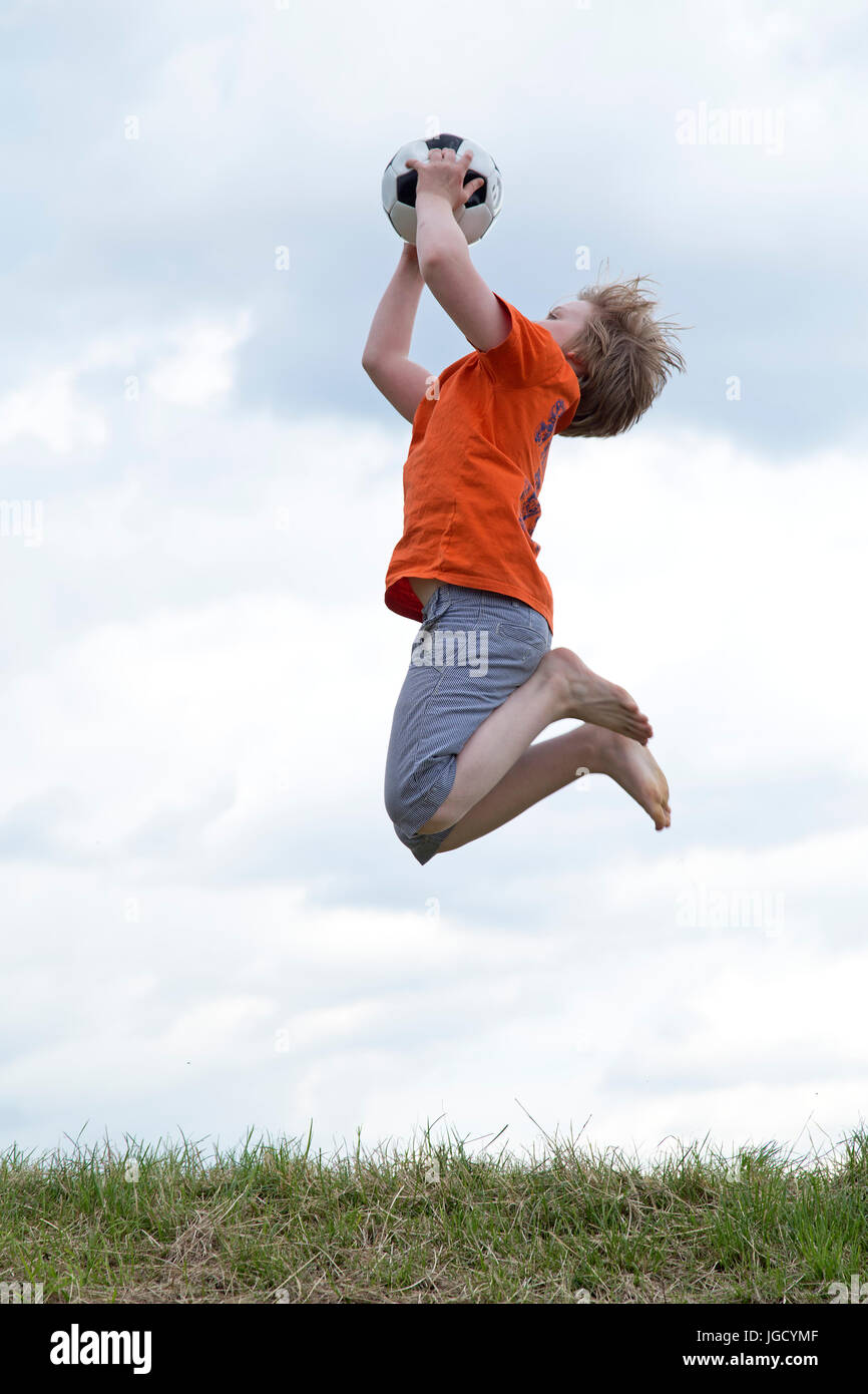 young boy jumping to catch a ball Stock Photo