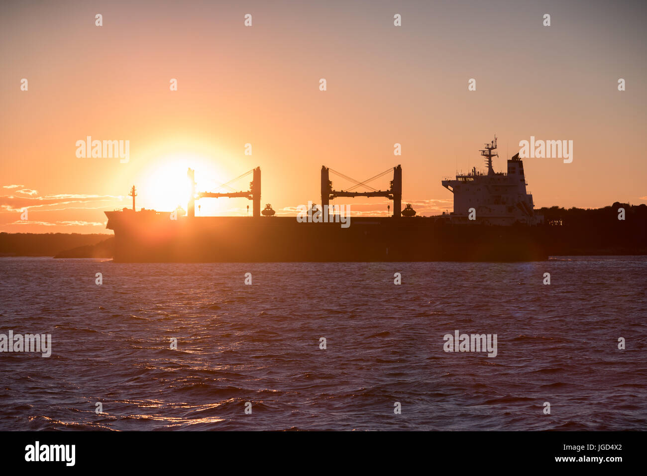Silhouette of cargo ship at sunset Stock Photo