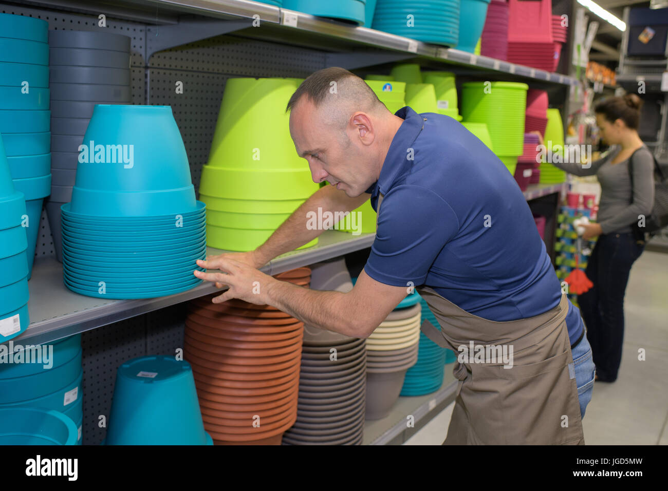 man tidying up colorful pots at a shope Stock Photo
