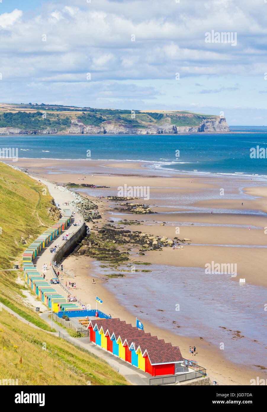 View over beach huts at Whitby towards Sandsend and Kettleness nab. North Yorkshire, England, UK Stock Photo