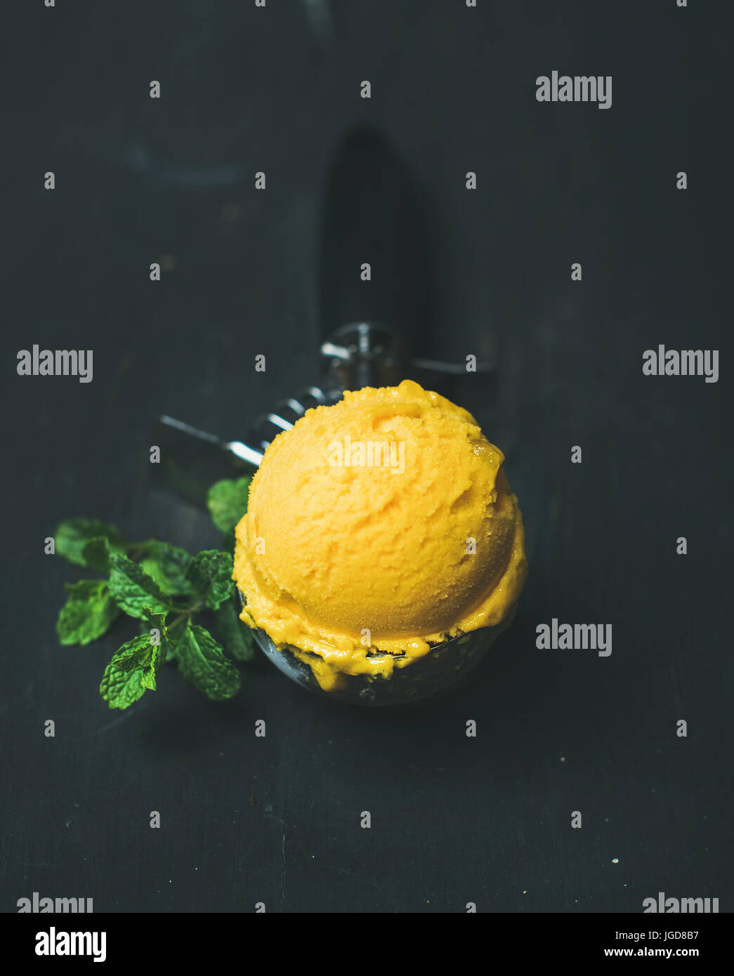 https://c8.alamy.com/comp/JGD8B7/mango-sorbet-ice-cream-scoop-in-scooper-over-black-background-JGD8B7.jpg