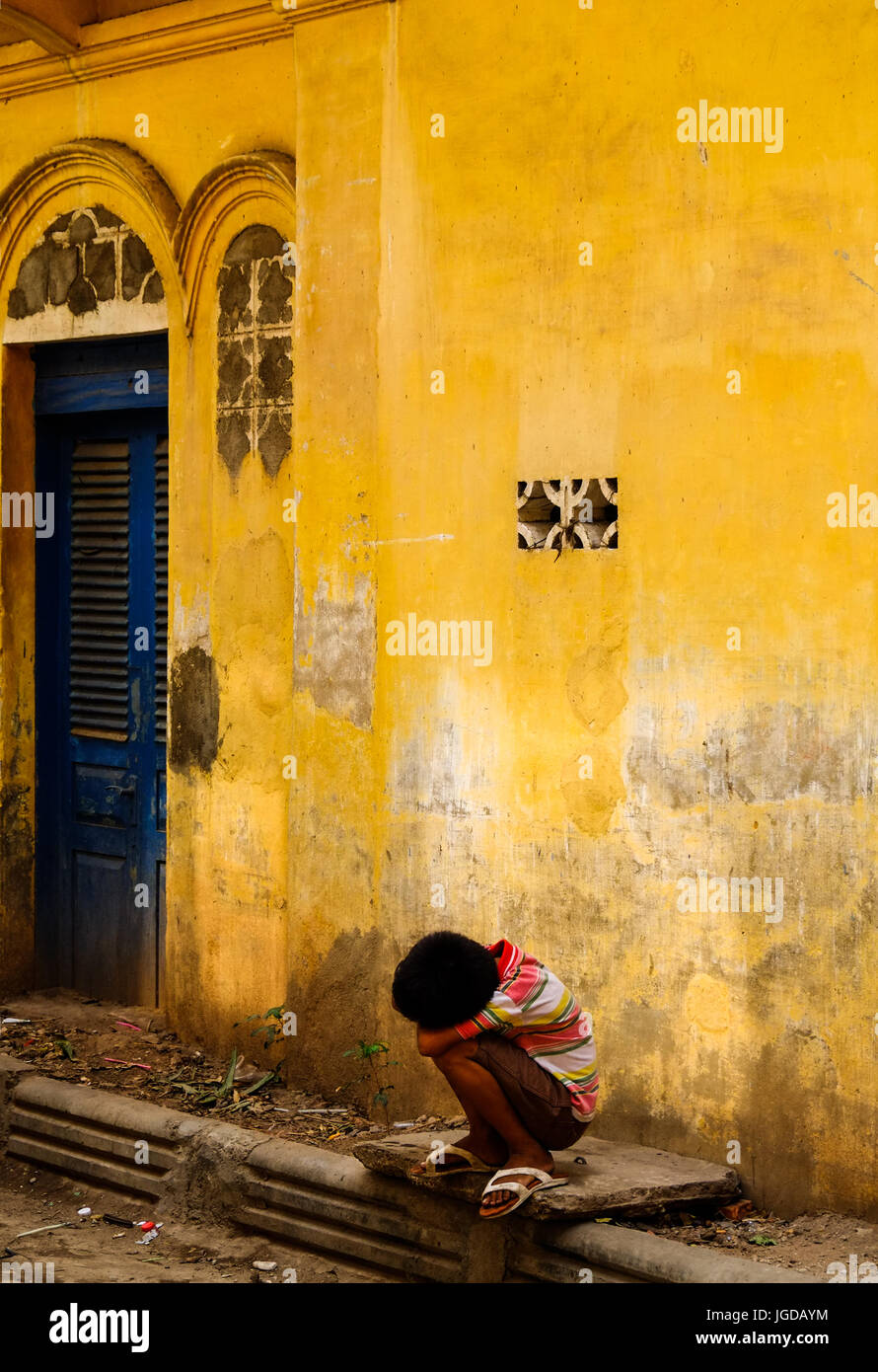 A Khmer boy sits outside an old building in Phnom Penh, Cambodia Stock Photo
