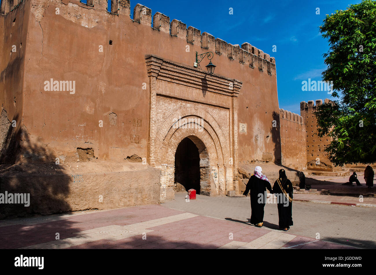 Africa, Morocco, Taroudannt, Veiled Muslim woman walking through arch in old city wall. Stock Photo