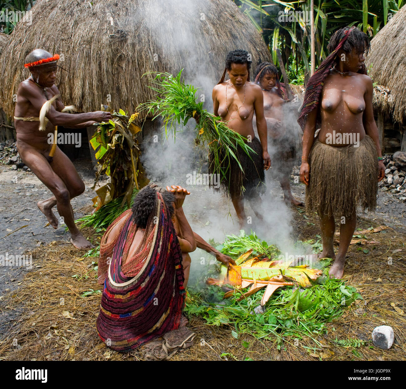 DANI VILLAGE, WAMENA, IRIAN JAYA, NEW GUINEA, INDONESIA – 25 JULY 2009: The women of the Dani tribe prepare food in a traditional earth oven. Stock Photo