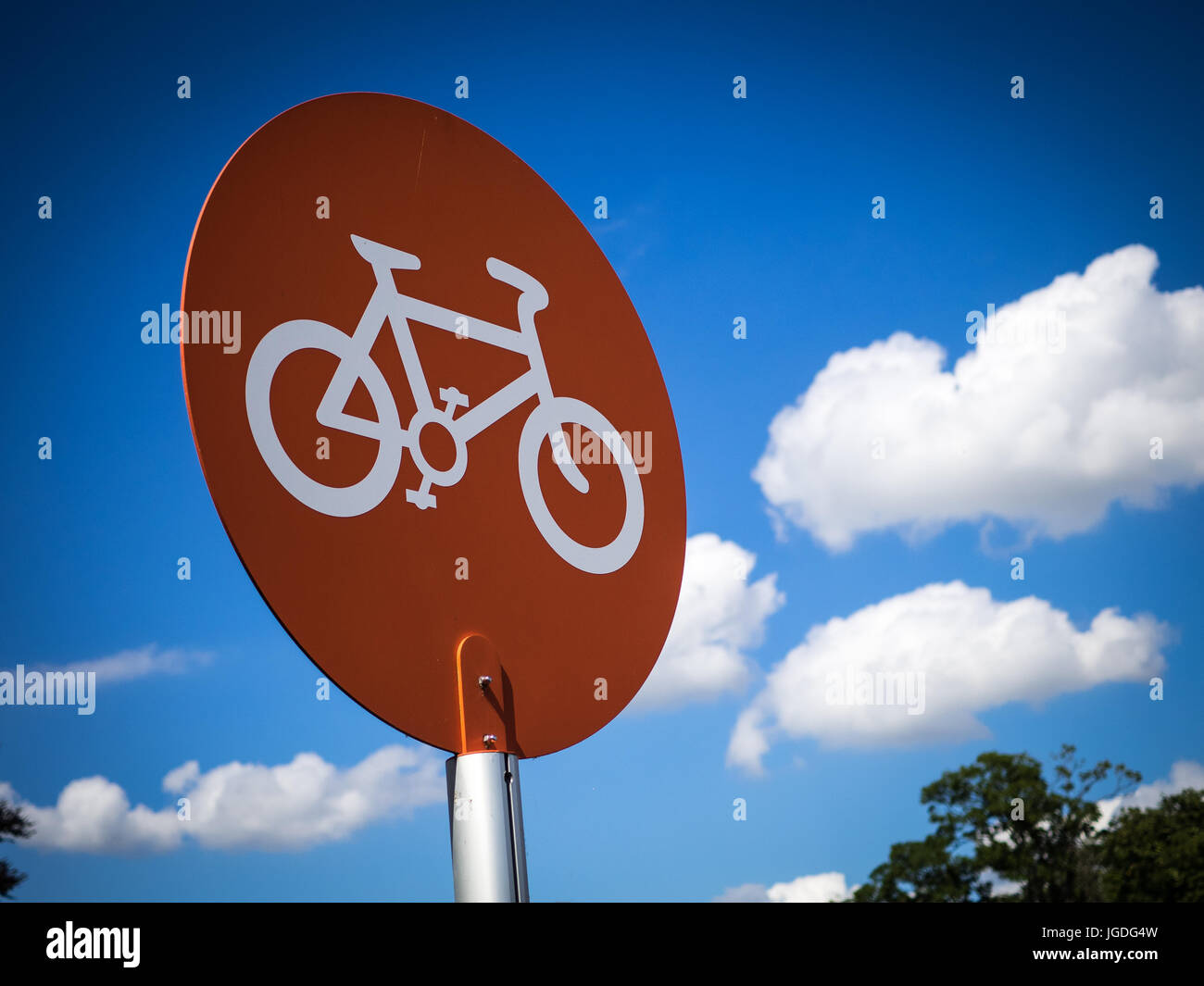 Orange bike parking sign against a cloudy blue sky Stock Photo