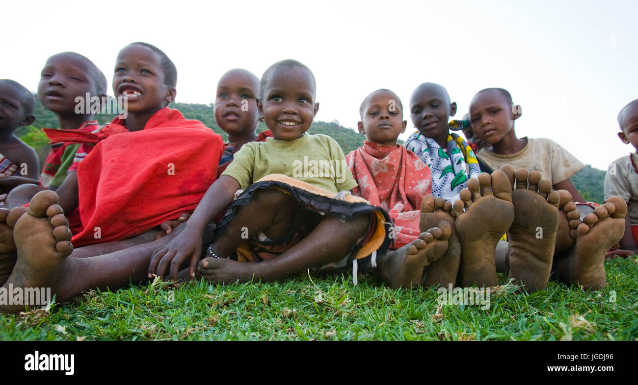 KENYA, MASAI MARA - JULY 19, 2011: Maasai children sit together on the ground. Stock Photo