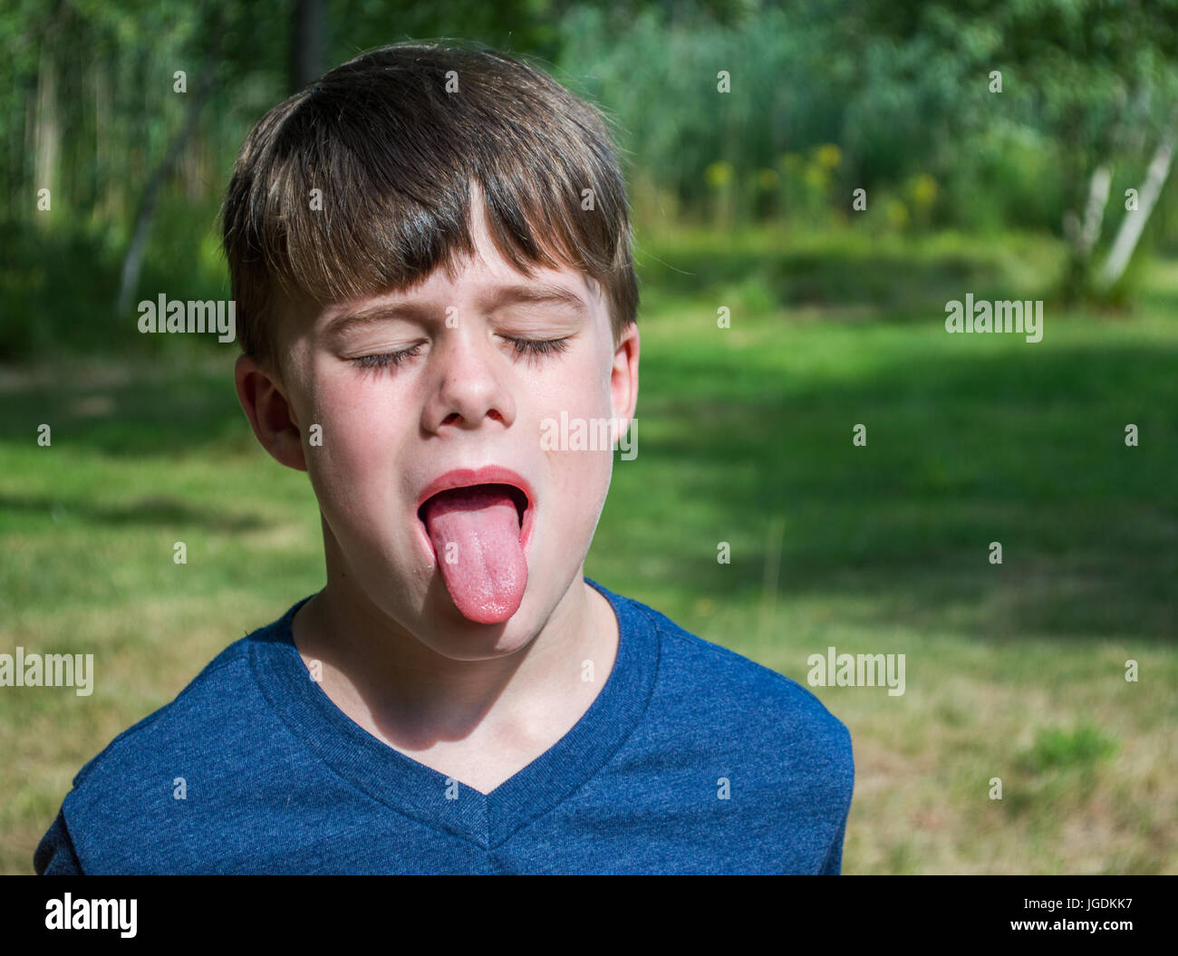 caucasian young boy outdoors sticking tongue out Stock Photo