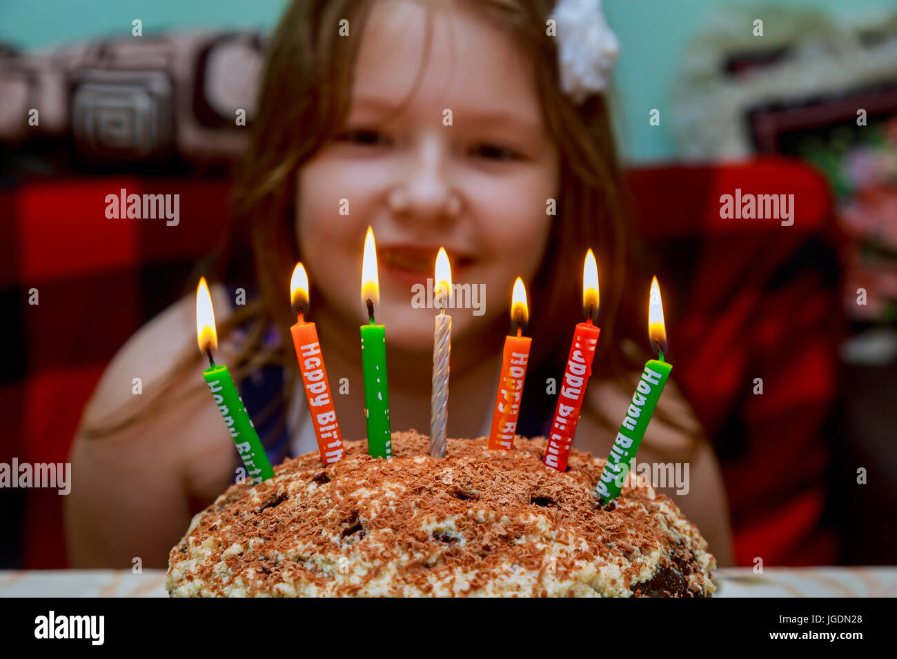 Little girl blowing candles Birthday cake with candles on purple