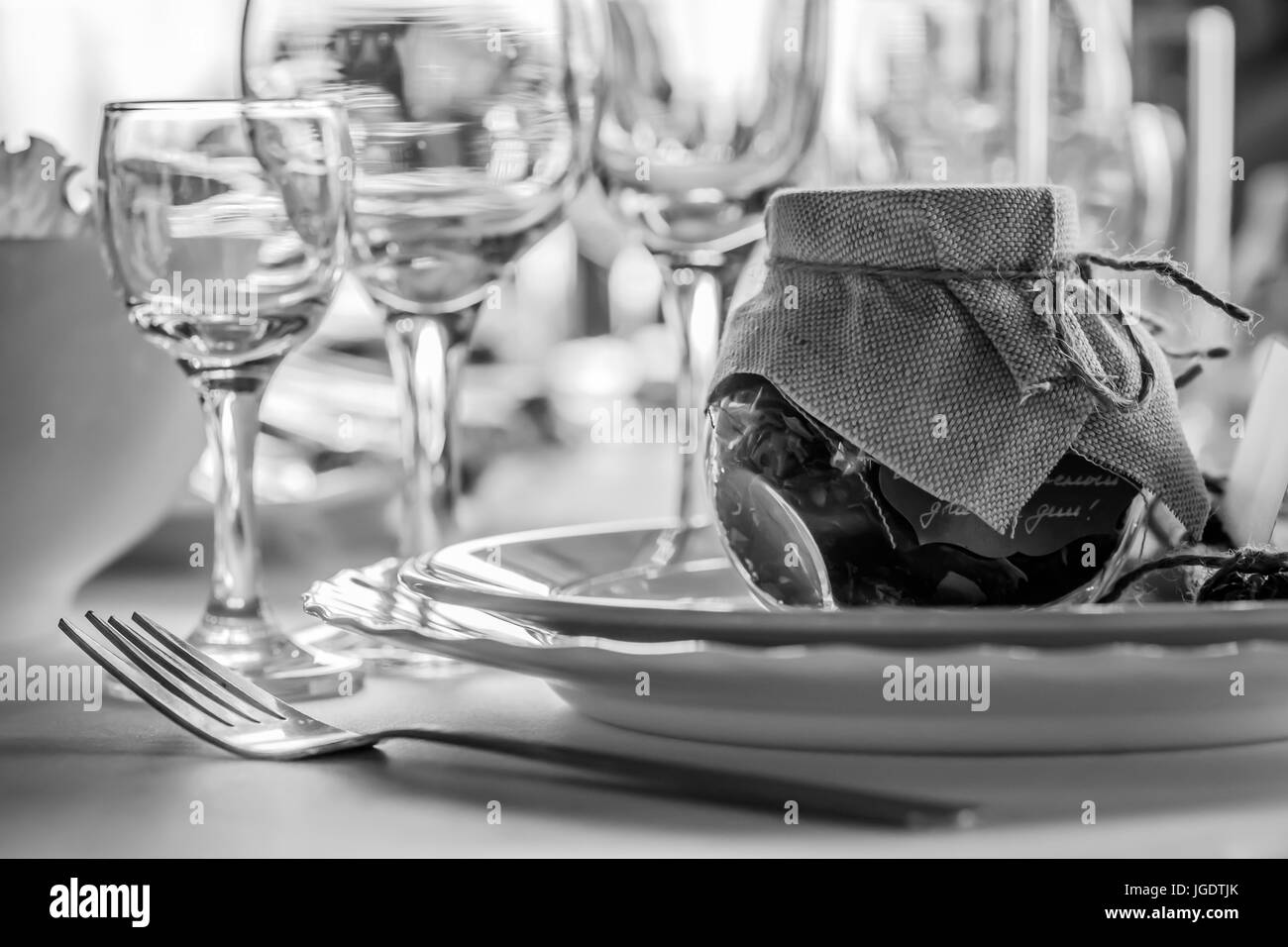 Rustic table setting for a wedding celebration in nice cozy restaurant. Wineglasses, plates and food on table. Guests complement in a rustic jar Stock Photo