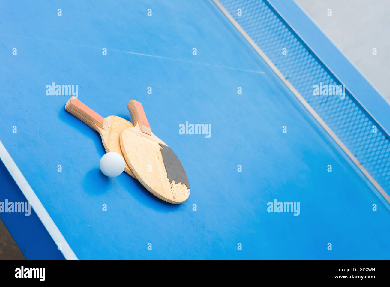 old pingpong rackets and ball and net on a blue pingpong table Stock Photo