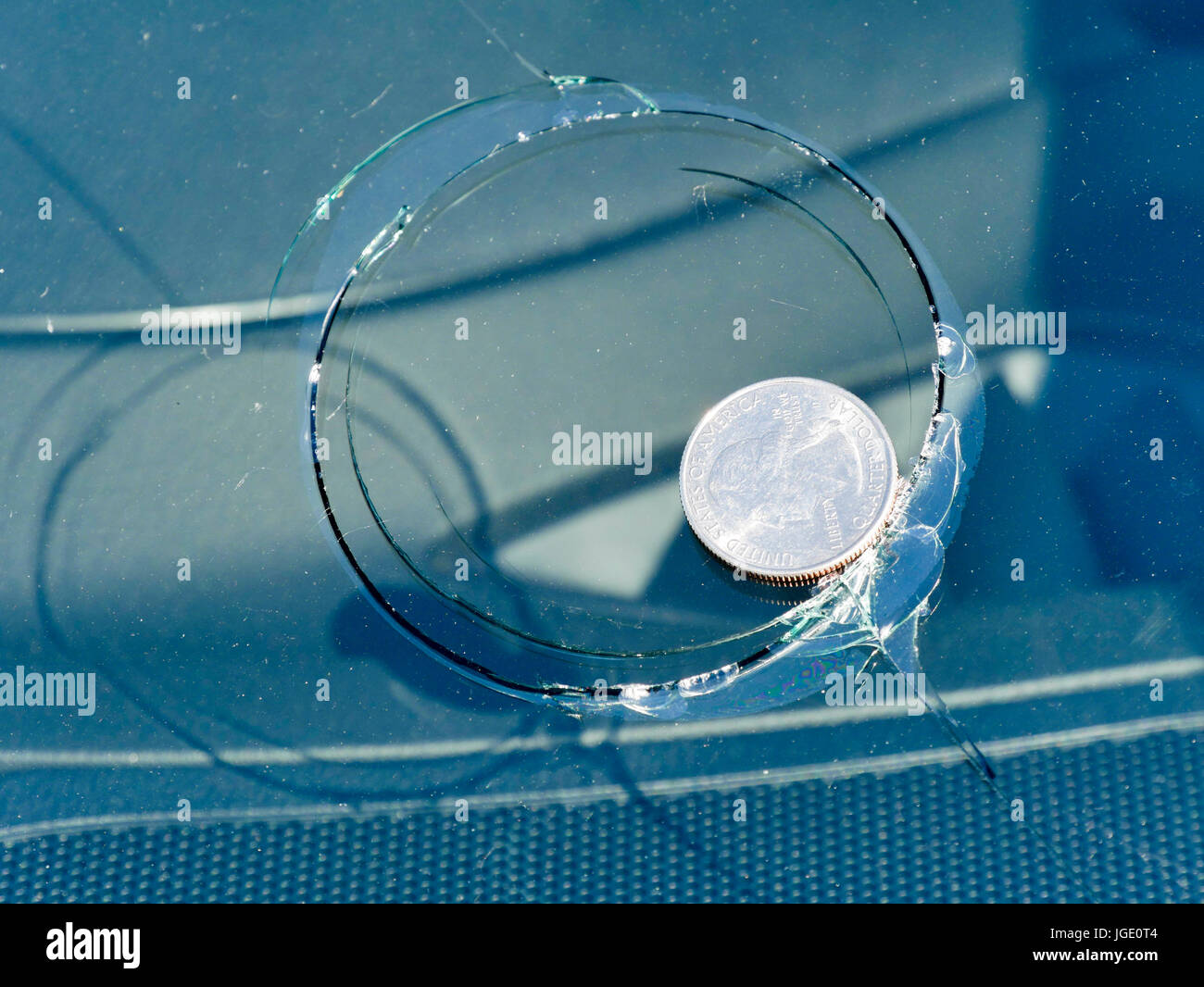 Damage to vehicle windshield caused by massive hailstone. U.S. Quarter
