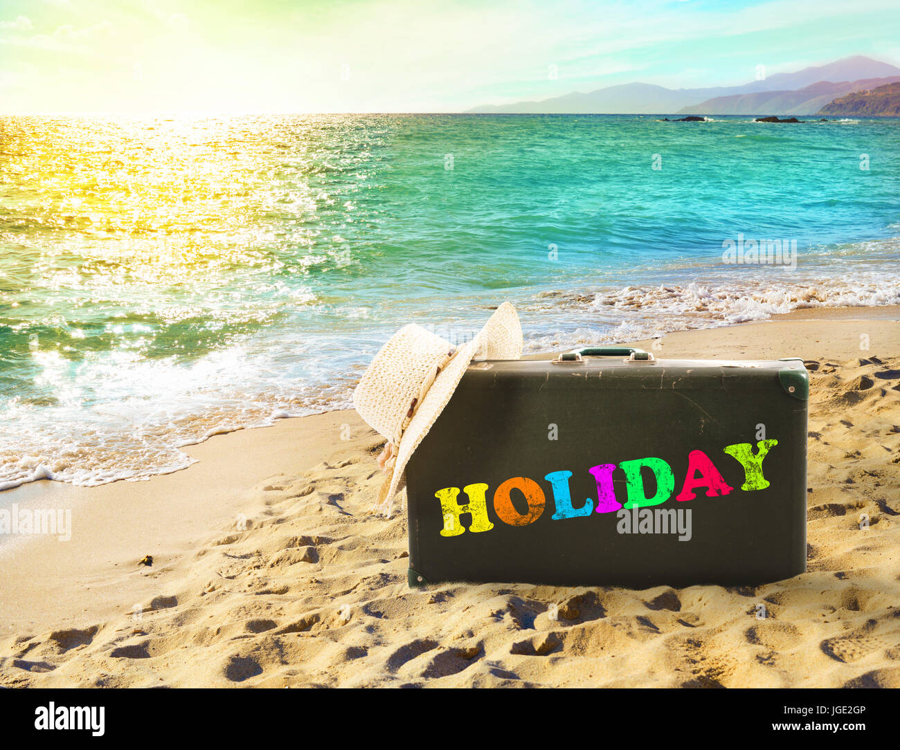 Suitcase in a tropical beach with holiday writing Stock Photo