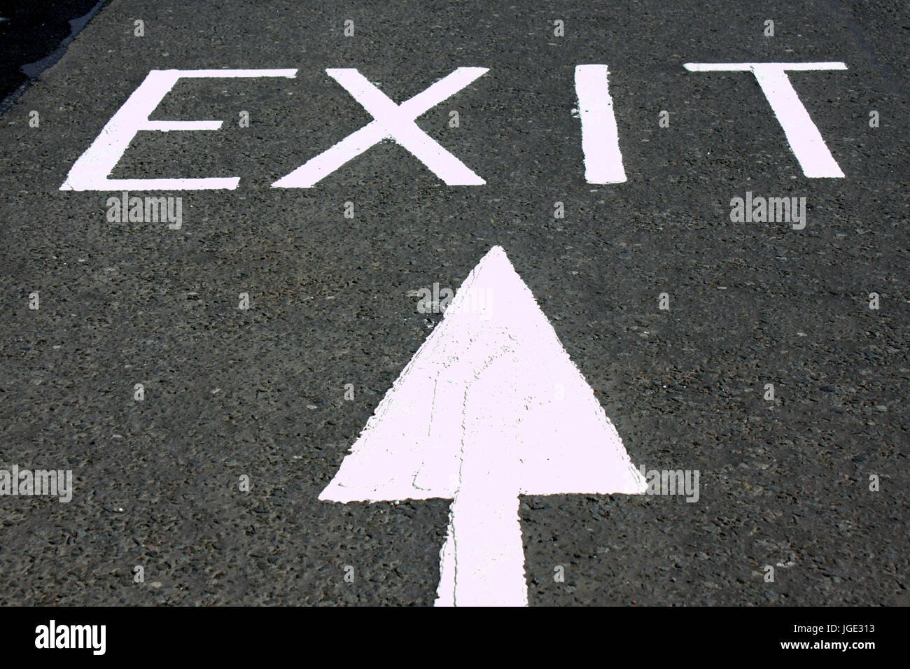exit sign arrow on asphalt tarmac white on grey black Stock Photo
