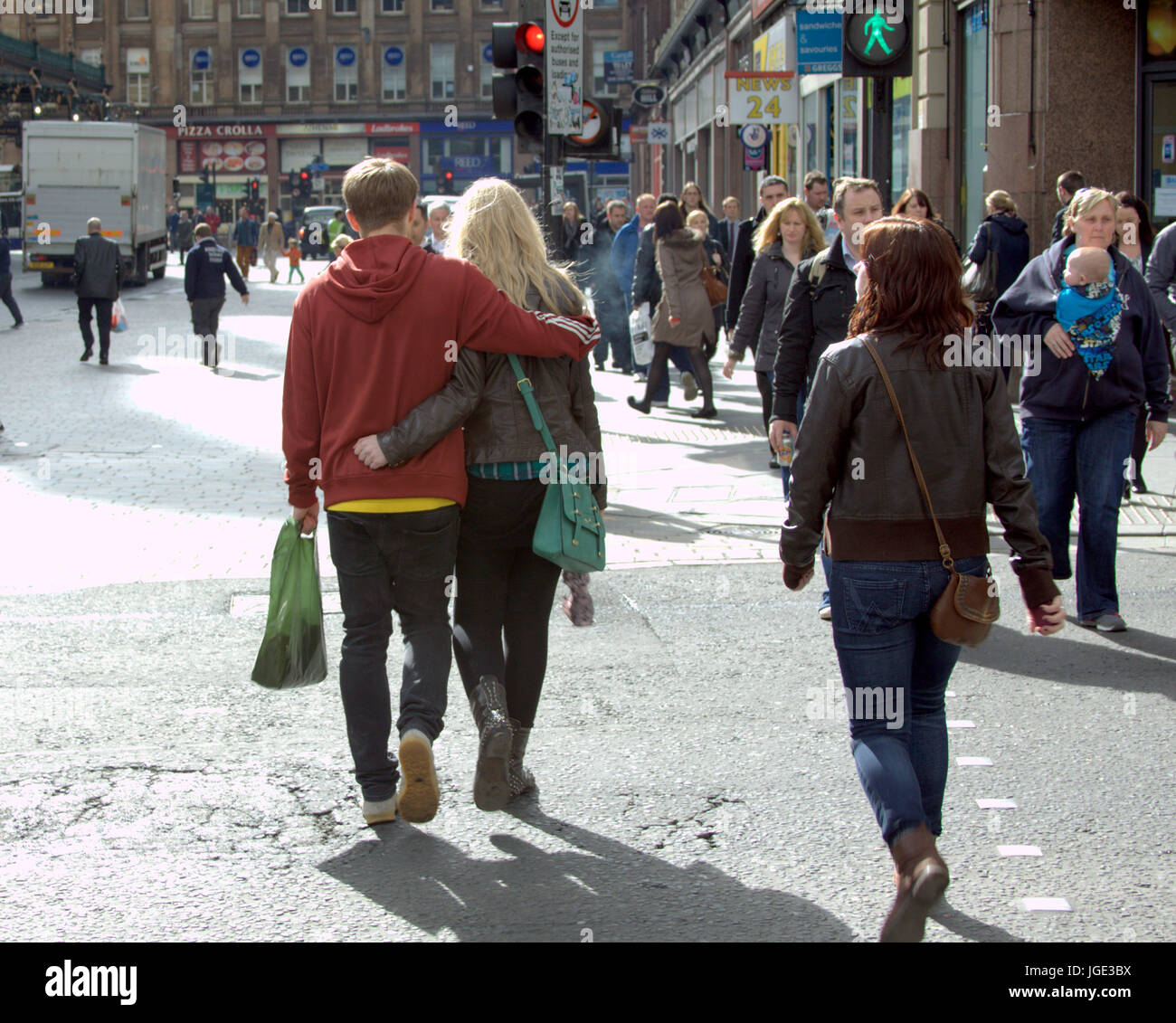 Glasgow street young couple in love with arms around each other walking hand in hand in step Stock Photo