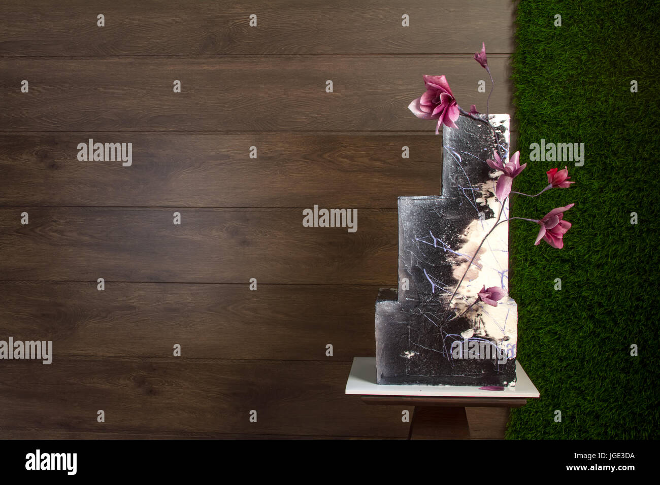 Beautiful tiered birthday cake on a dark wooden background Stock Photo