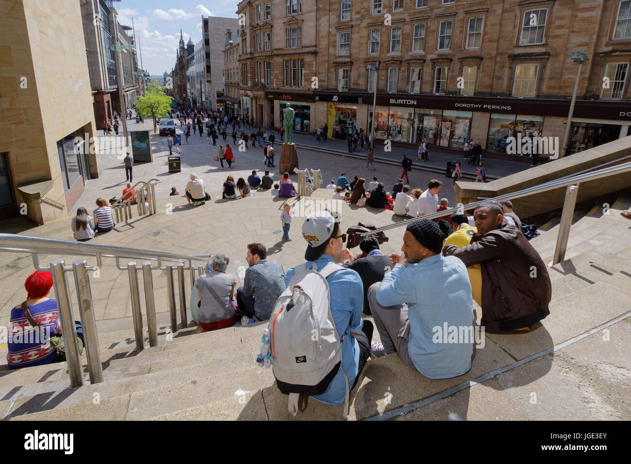 tourists and locals enjoy the sunny weather on the Sauchiehall street steps near the Donald Dewar statue Stock Photo