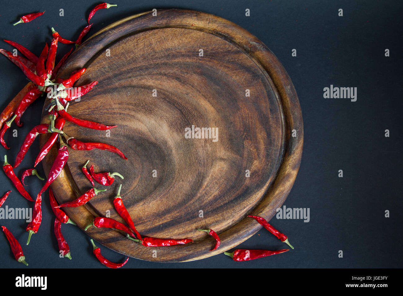 Red chili pepper and wooden board on a black background Stock Photo - Alamy