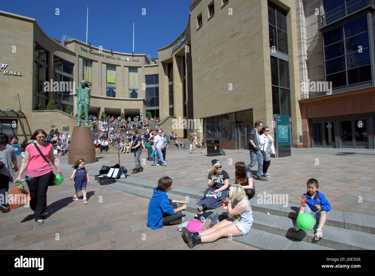 tourists and locals enjoy the sunny weather on the Sauchiehall street steps near the Donald Dewar statue Stock Photo