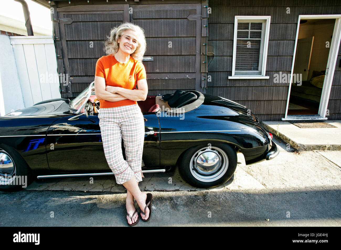 Portrait of older Caucasian woman leaning on convertible car Stock Photo