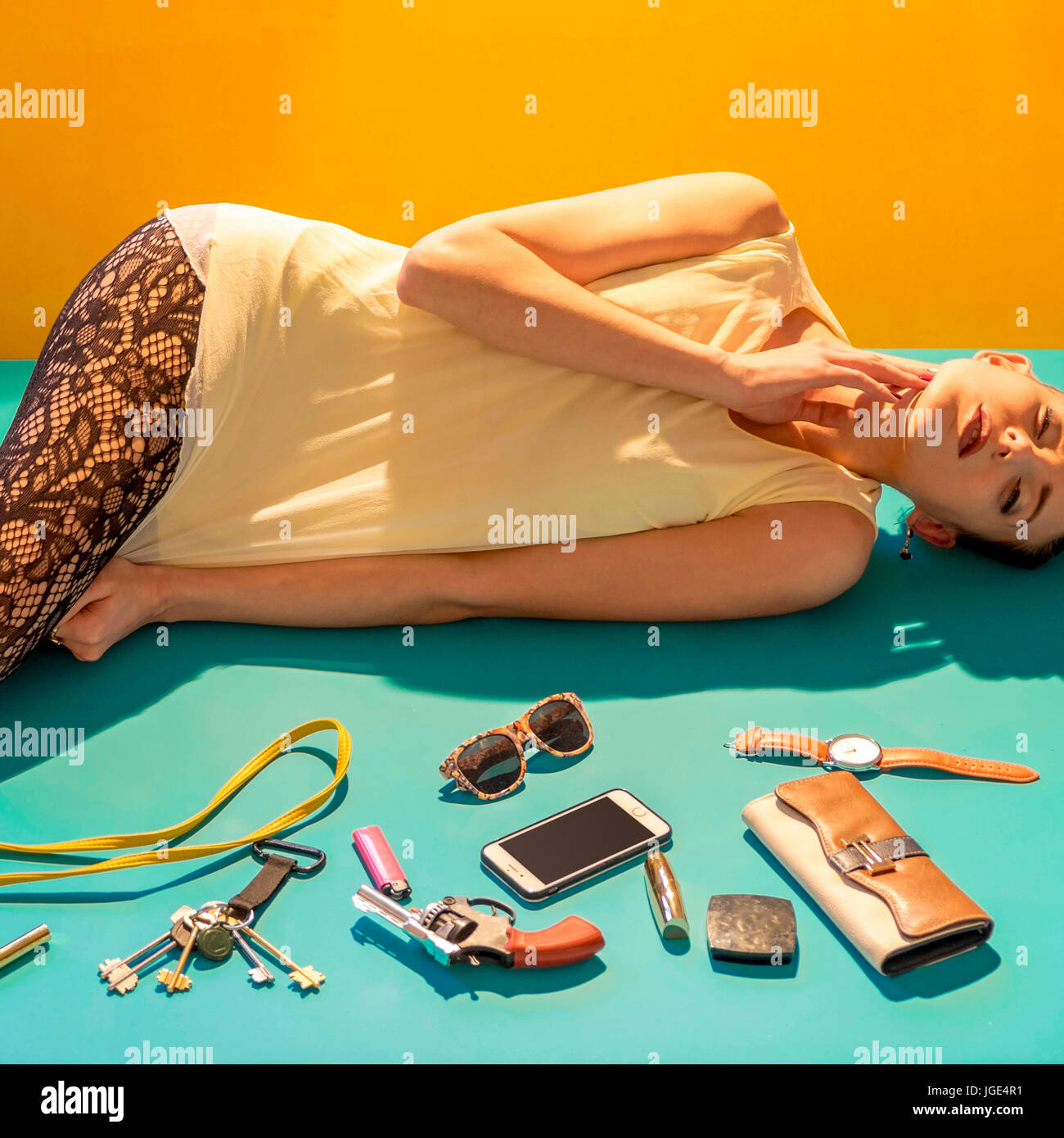 Caucasian woman laying on floor near wallet, gun and cell phone Stock Photo