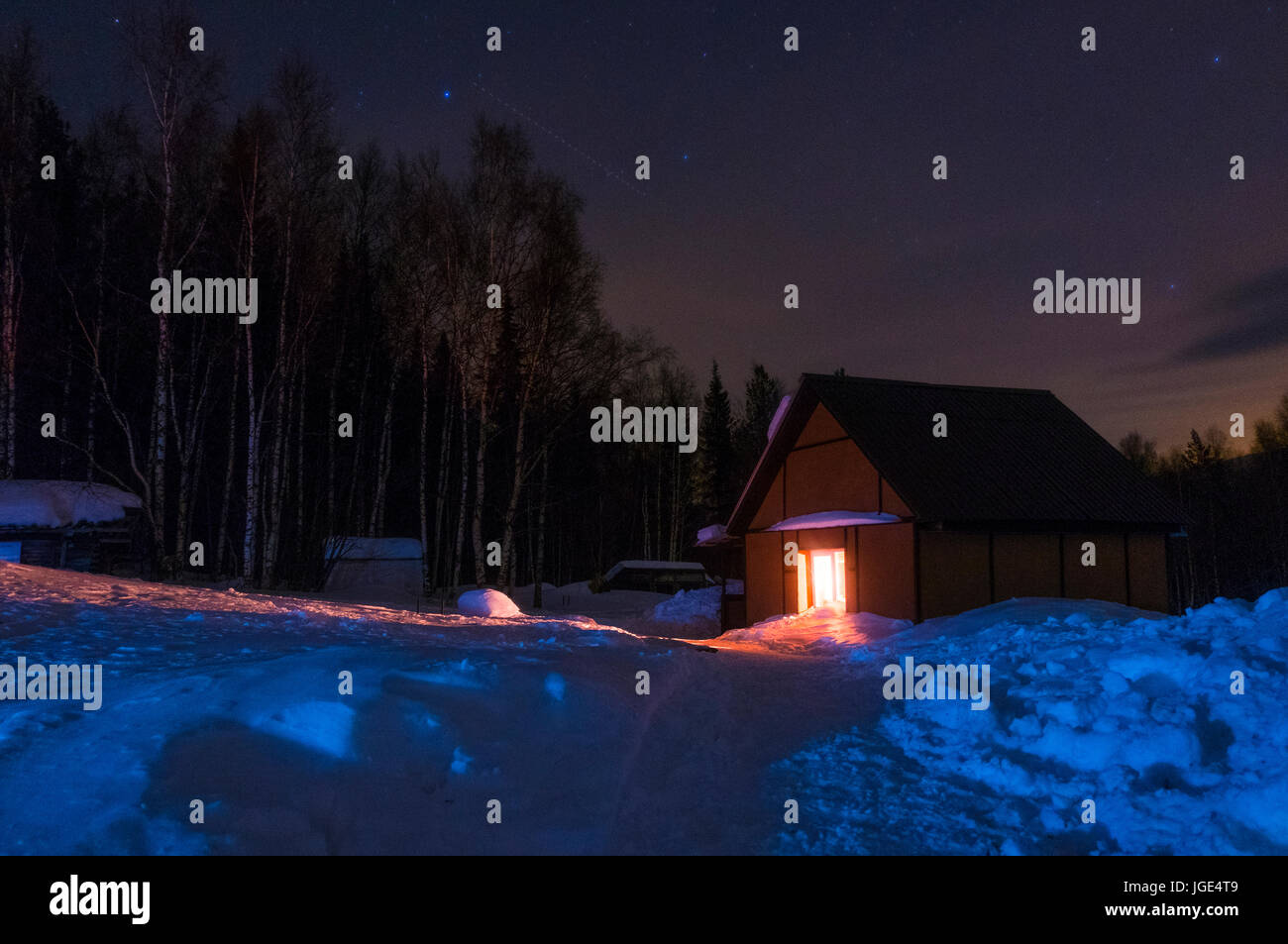 Light glowing in remote cabin in winter Stock Photo