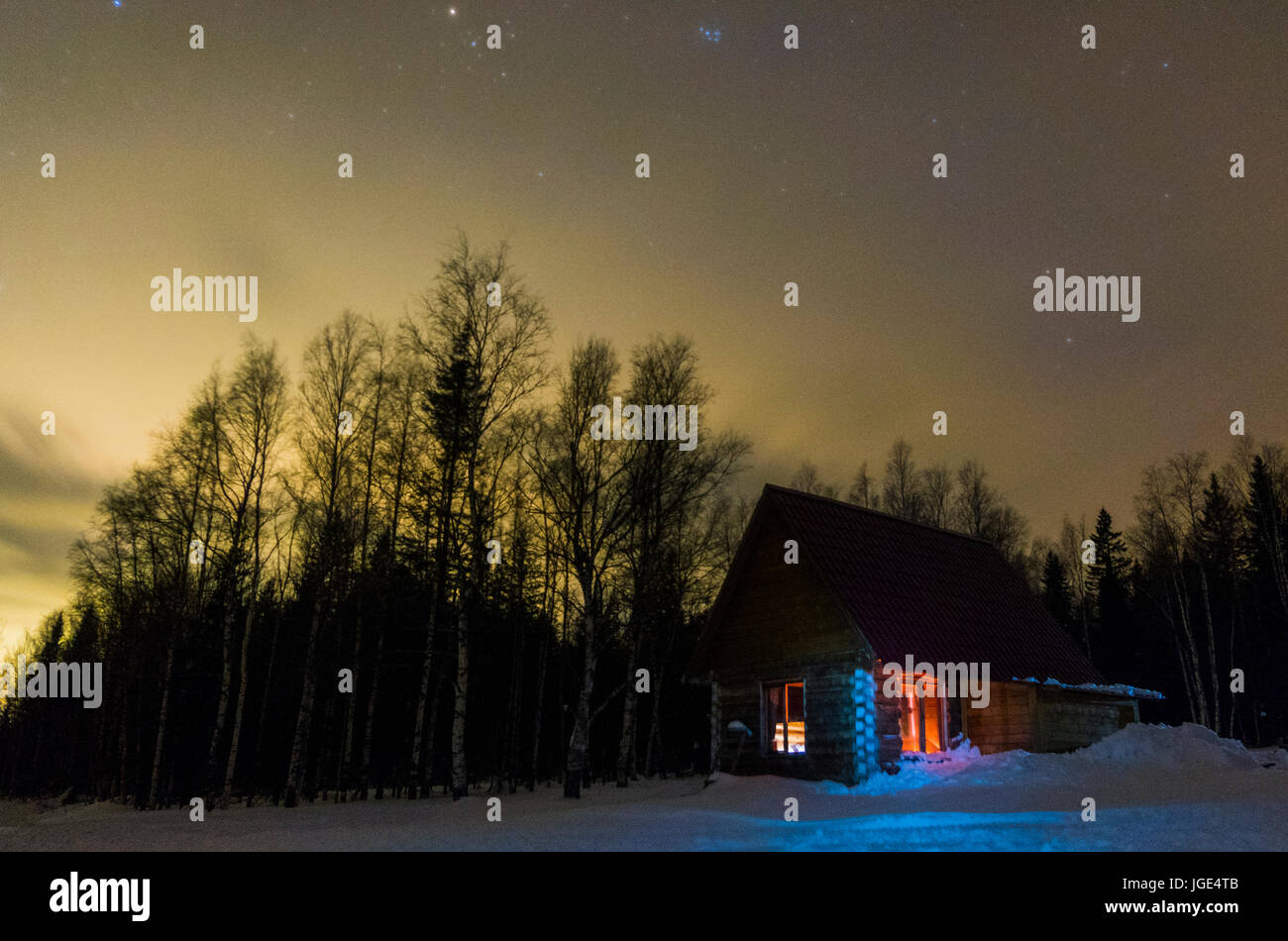 Light glowing in remote cabin in winter Stock Photo
