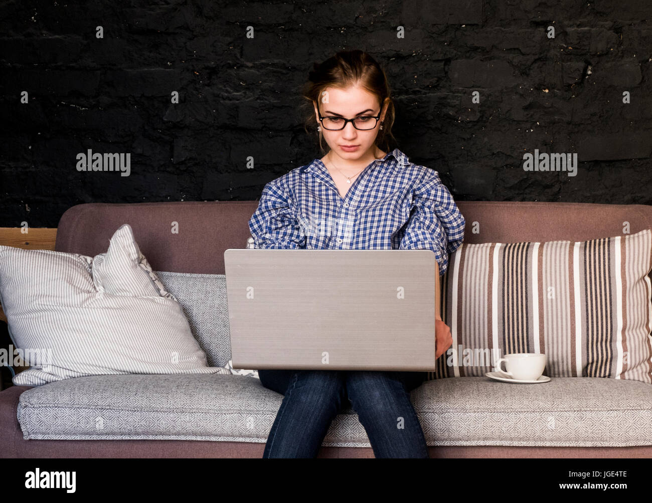 Caucasian woman sitting on sofa using laptop Stock Photo