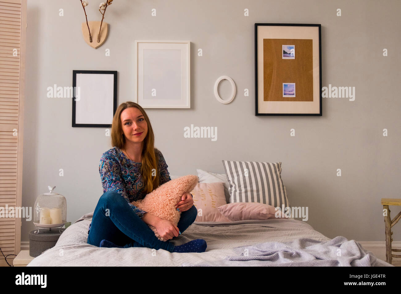 Portrait of smiling Caucasian woman sitting on bed Stock Photo
