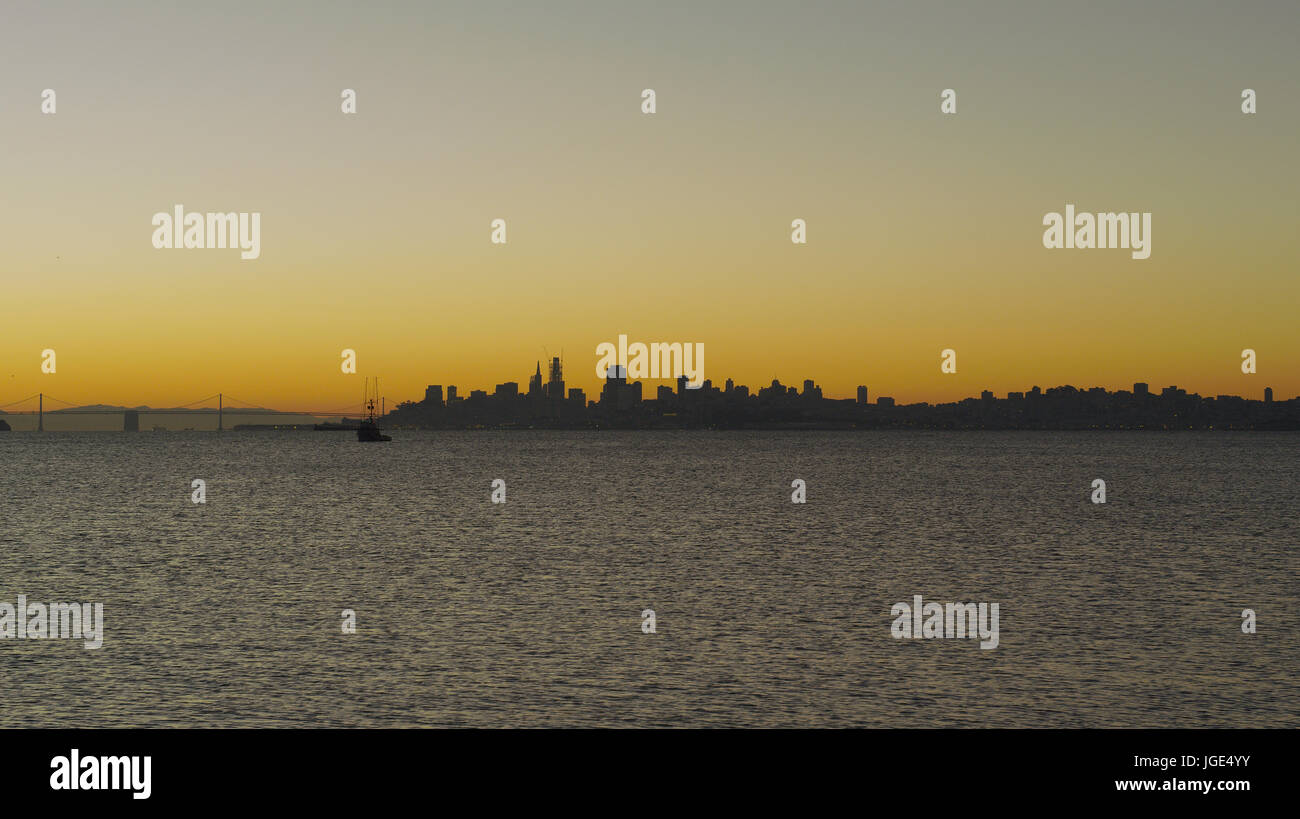 Silhouette of urban waterfront skyline at sunset Stock Photo