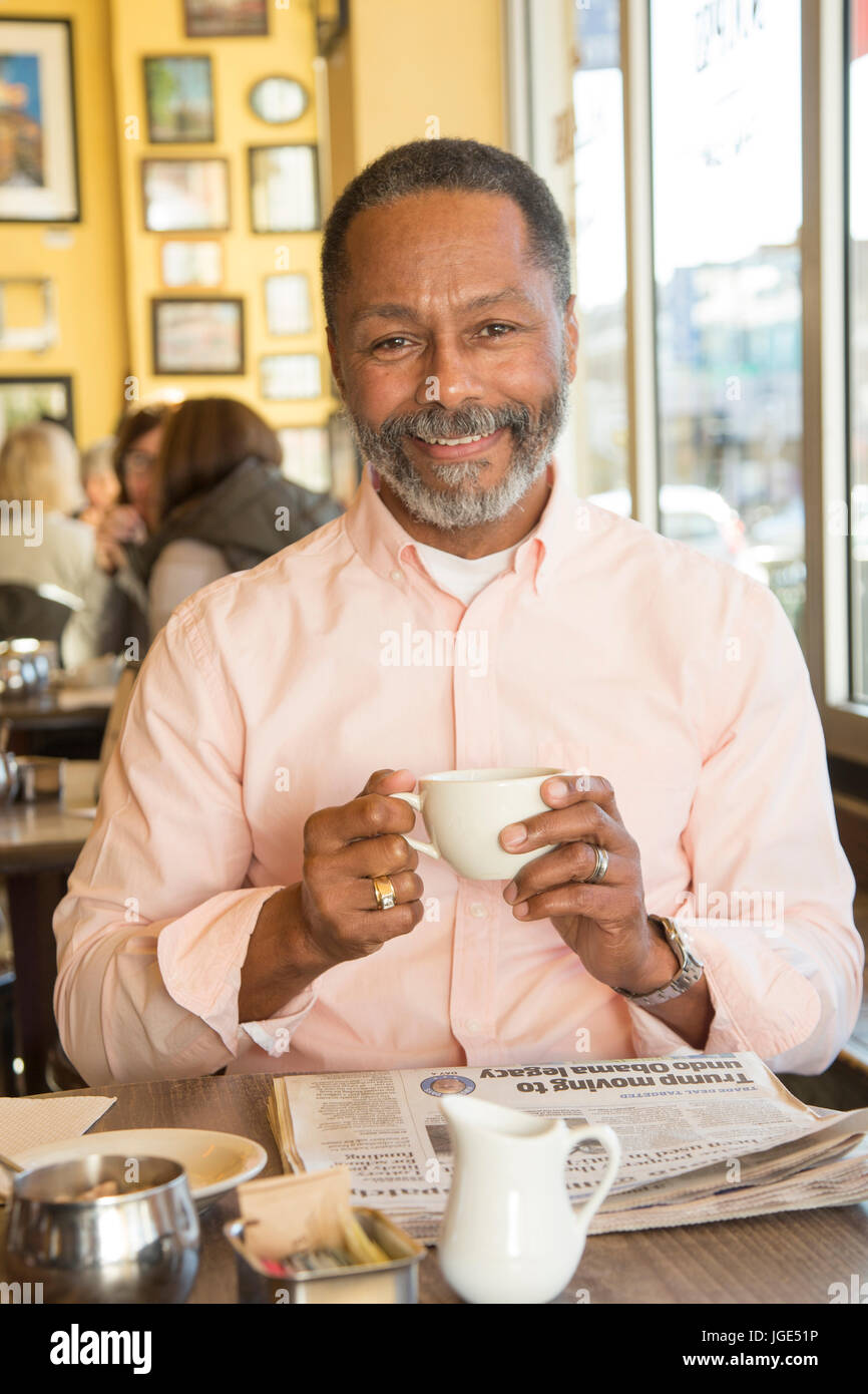 Mixed Race man drinking coffee in coffee shop Stock Photo