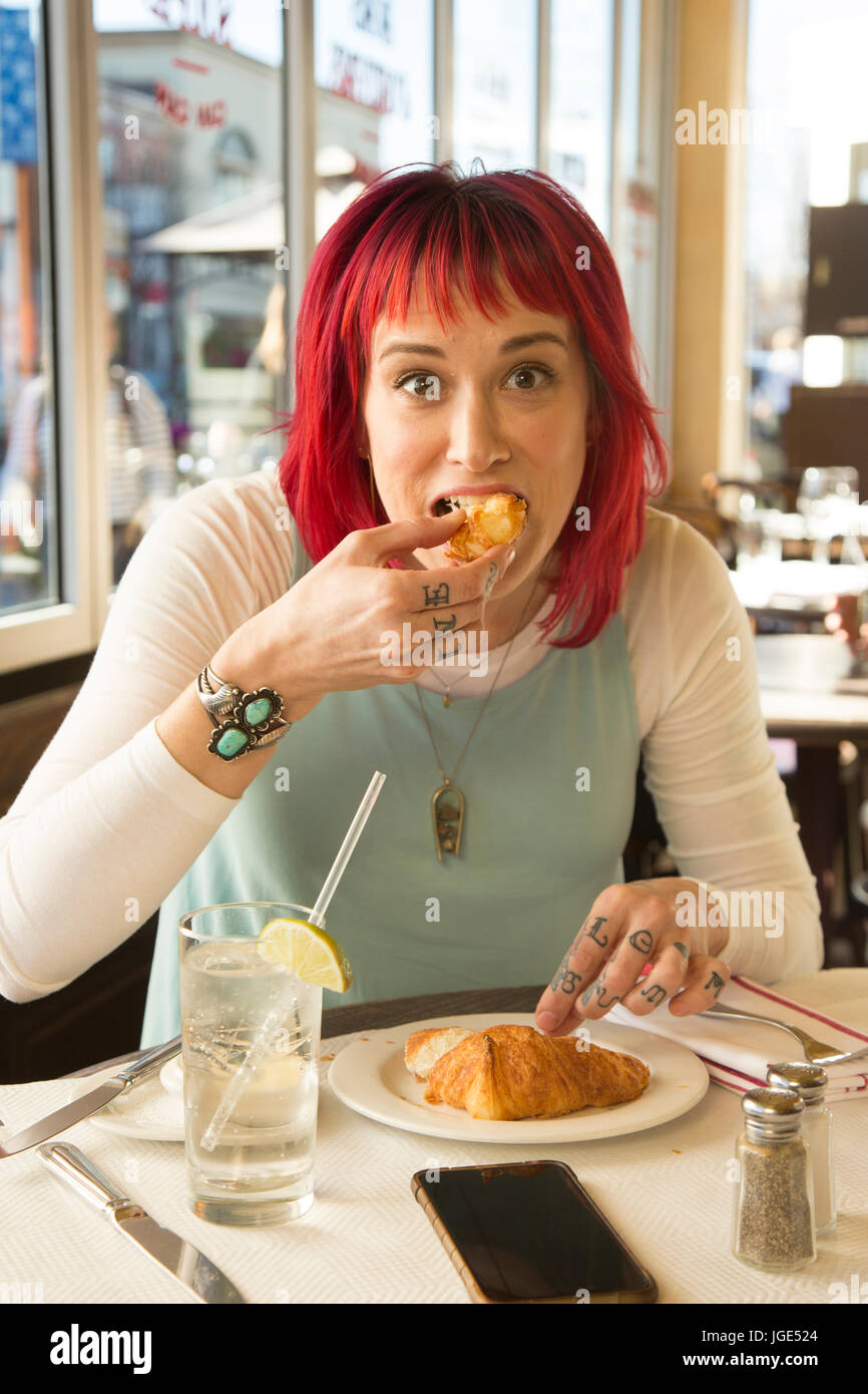 Caucasian woman eating croissant in restaurant Stock Photo