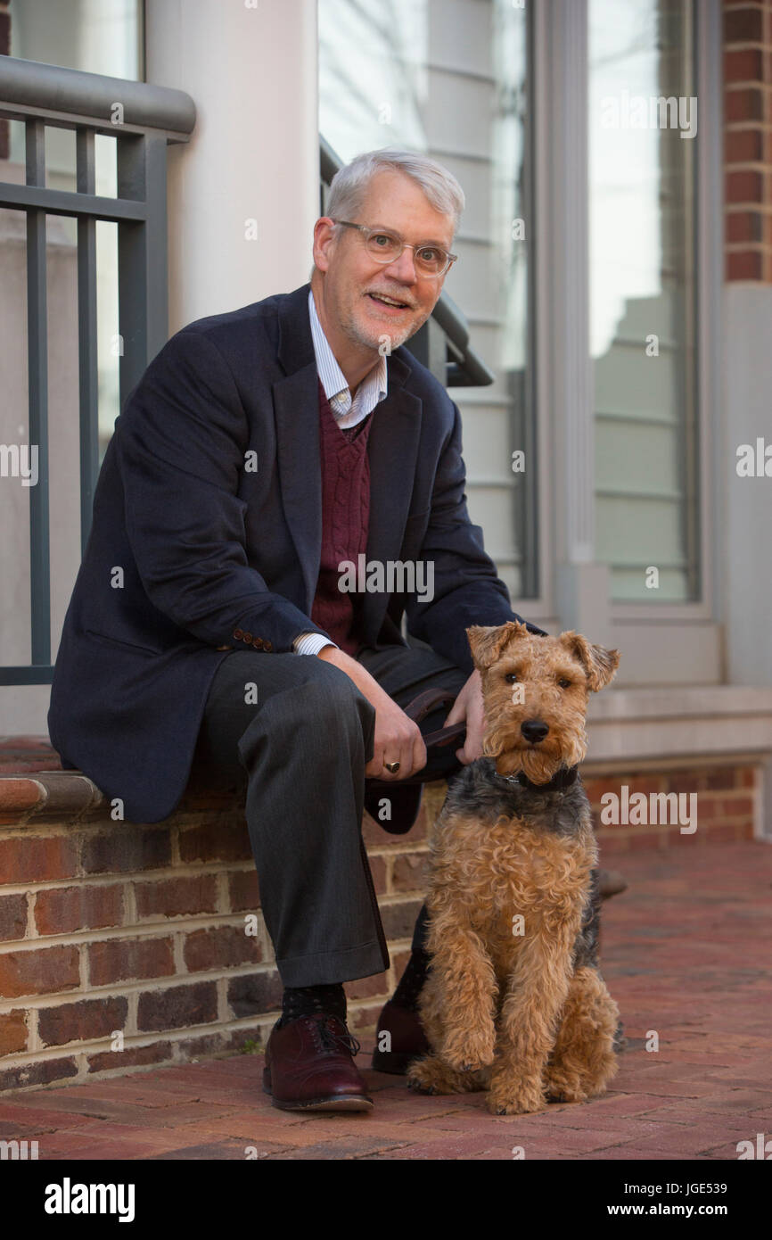 Portrait of Caucasian man sitting on stoop posing with dog Stock Photo